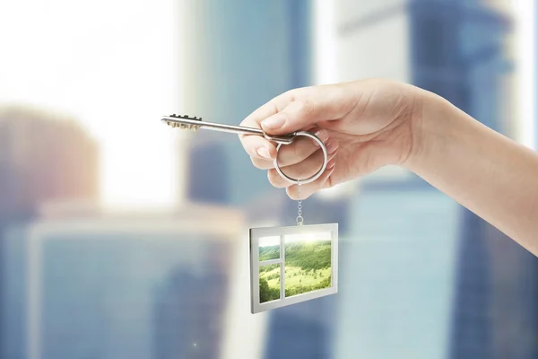 Hand holding key with a keychain in the shape of the window — Stock Photo, Image