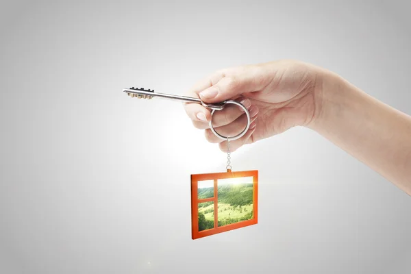 Ręka trzyma klucz z breloczek w kształcie okna — Zdjęcie stockowe