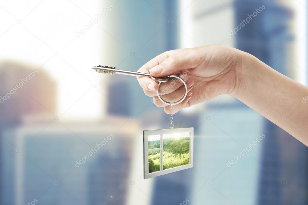 Hand holding key with a keychain in the shape of the window