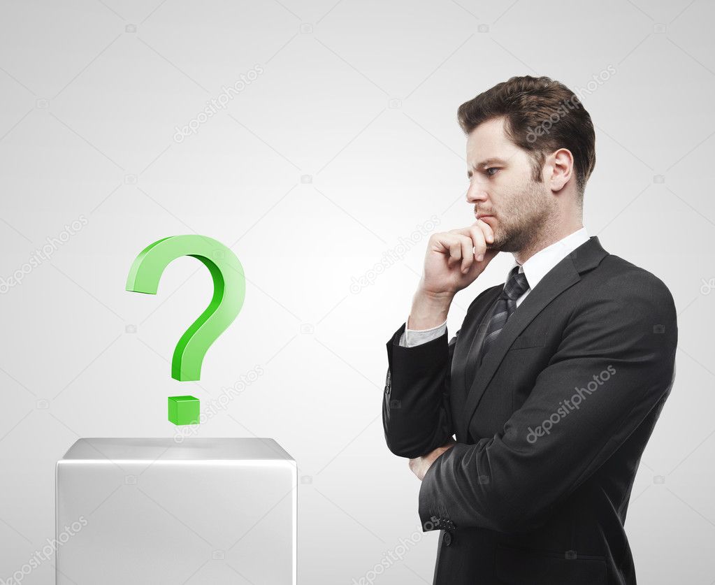 Young businessman look at the green question mark on a white pedestal.