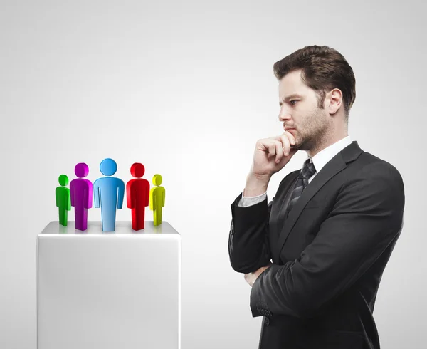 Young businessman look at the group of social on a white pedestal. — Stock Photo, Image
