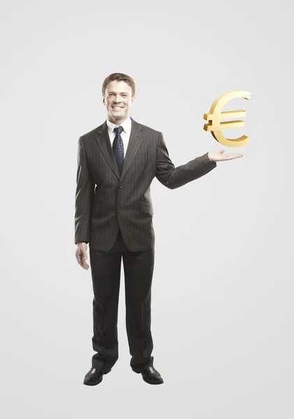 Młody biznesmen wybiera złoty znak euro — Zdjęcie stockowe