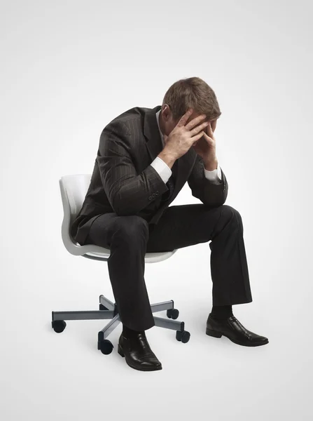 Jungunternehmer sitzt mit gesenktem Kopf auf Stuhl, als ob er traurig oder deprimiert wäre. — Stockfoto