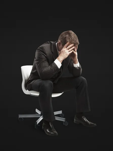 Jonge zakenman zitten op de stoel met hoofd alsof verdrietig of depressief. — Stockfoto