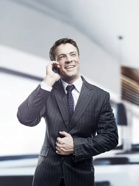 Портрет счастливого бизнесмена, разговаривающего на мобильном телефоне, стоящего в офисе, улыбающегося — стоковое фото