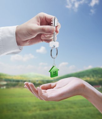 Man is handing a house key to a woman. clipart