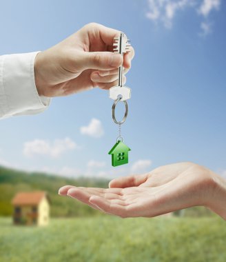 Man is handing a house key to a woman. clipart