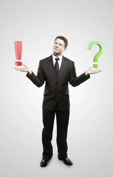 Young businessman with a question and exclamation mark on his hand. — Stock Photo, Image