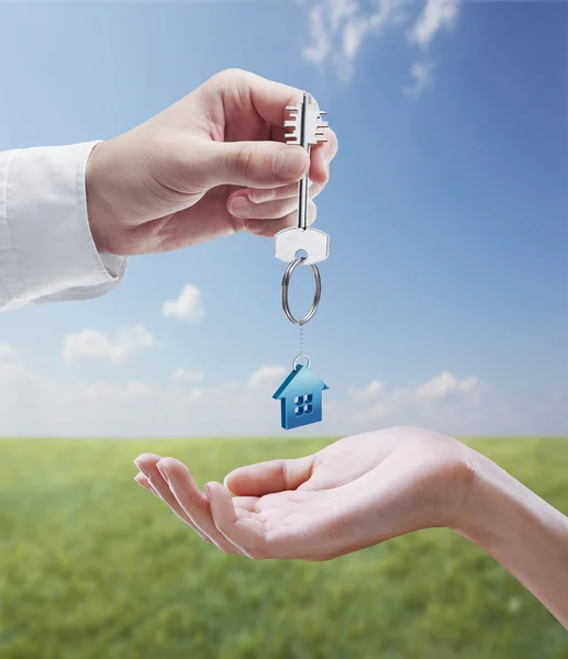 Man is handing a house key to a woman. — Stock Photo, Image