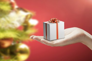 Gift box on a female hand. On a red background. clipart