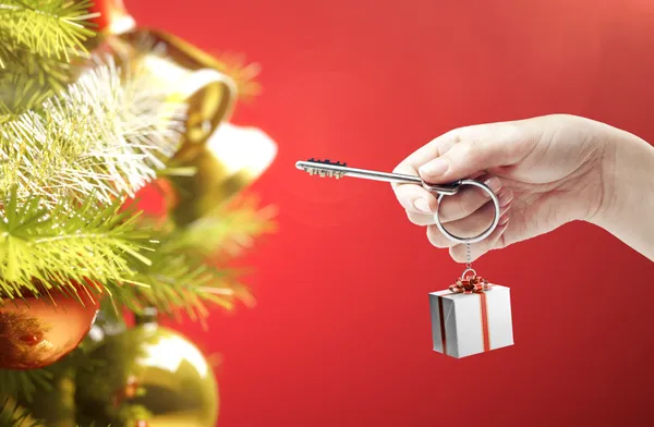 Hand ingedrukt met een sleutelhanger in de vorm van de doos van de gift. — Stockfoto