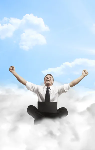 Happy young businessman with laptop sitting on the clouds. — Stock Photo, Image