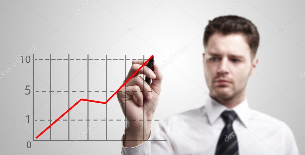 Young business man drawing a graph on a glass window in an office
