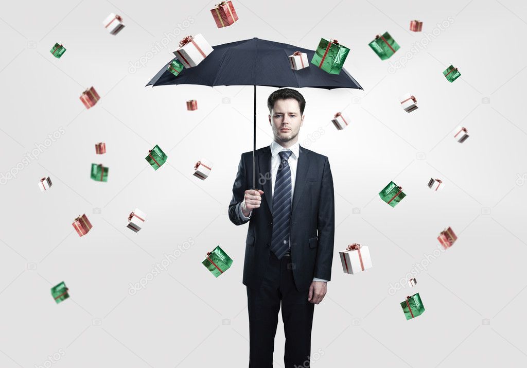 Young Business man with umbrella under gift boxes rain.