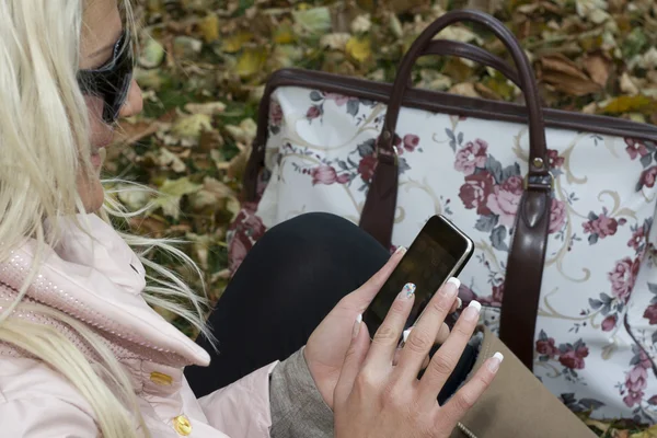 Vrouw met een mobiele telefoon in het park — Stockfoto