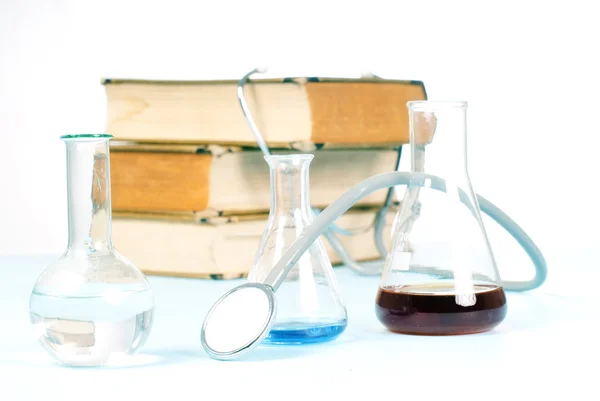 stock image Stethoscope and flask in front of books.