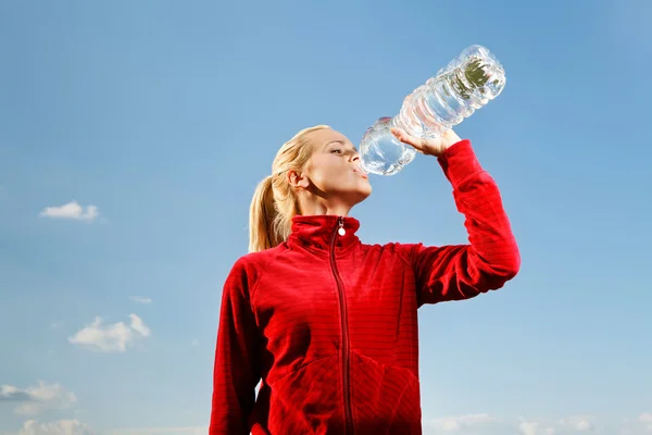 Mujer joven bebiendo agua de botella de plástico — Foto de Stock