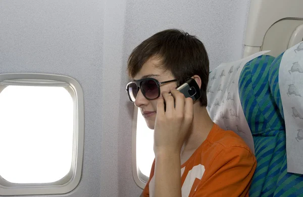 Teenager talking a mobile phone in a plane — Stock Photo, Image