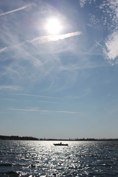 Barco en un lago bajo un cielo azul —  Fotos de Stock