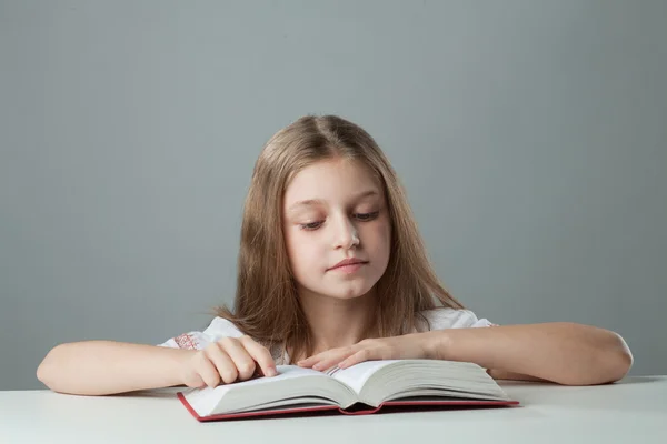Kız masada bir kitap okuma — Stok fotoğraf