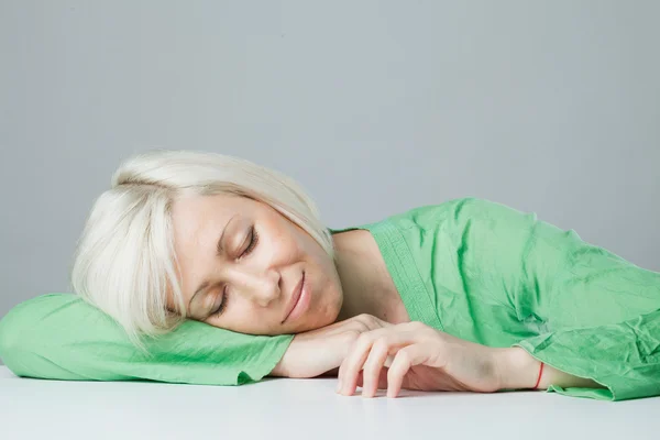 Spící žena v zelených šatech u stolu — Stock fotografie