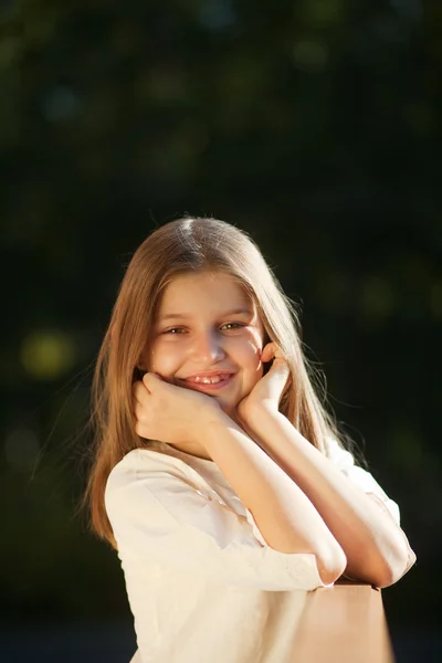 Chica se sienta apoyada en su cabeza con las manos y sonriendo —  Fotos de Stock