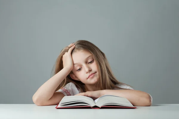 Девушка за столом читает книгу — стоковое фото