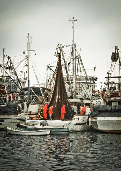 Команда рыбаков чинит сети на рыбацкой лодке — стоковое фото