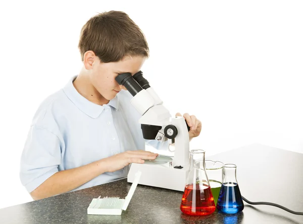 Criança olha através do microscópio — Fotografia de Stock