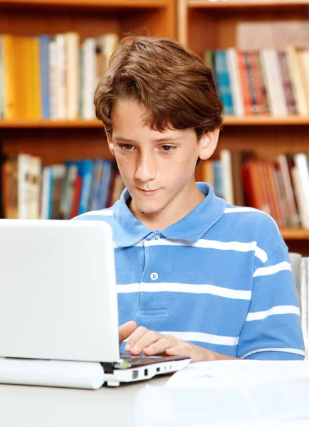 Chłopiec przy użyciu komputera w bibliotece — Zdjęcie stockowe