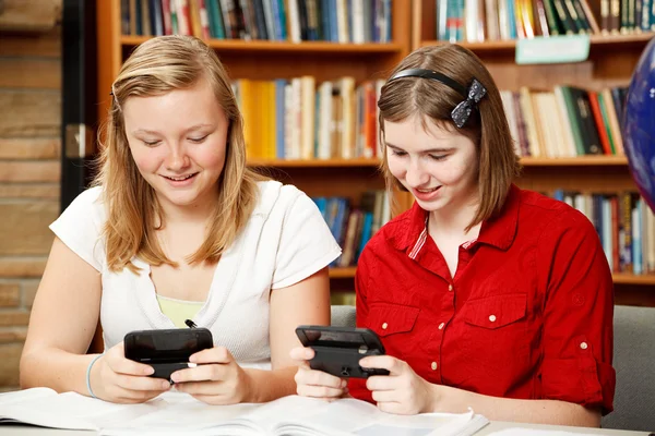 Tieners texting in bibliotheek — Stockfoto