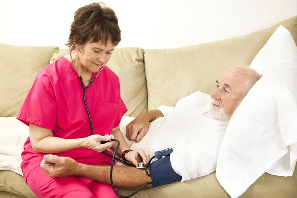 Home Enfermeira toma pressão arterial — Fotografia de Stock
