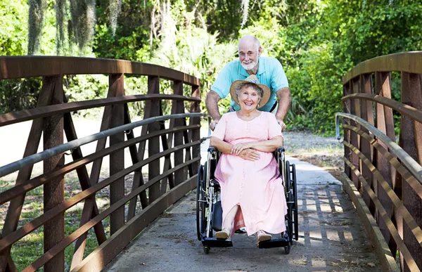 Senior schubst Frau im Rollstuhl — Stockfoto