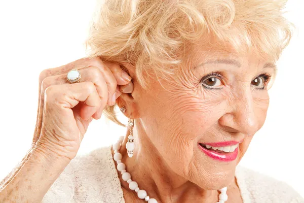 Старшая женщина вставляет слуховой аппарат — стоковое фото