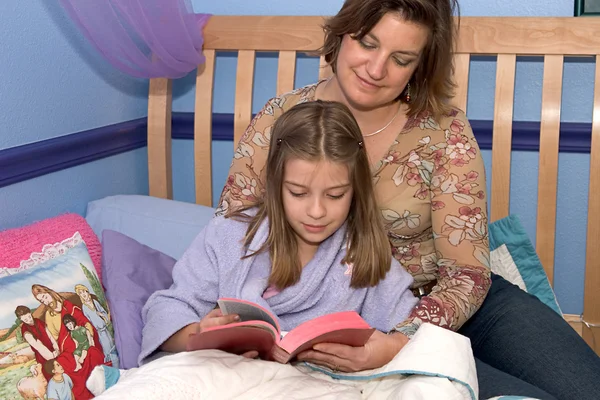 Мать и дочь вместе читают сказки на ночь — стоковое фото