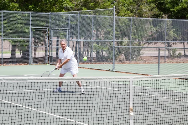 Старшая женщина играет в теннис — стоковое фото