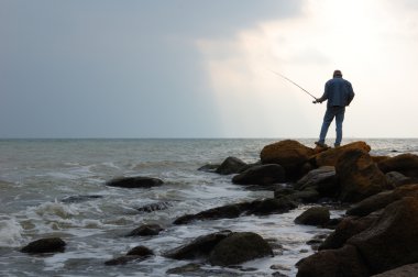 Fisherman on the sea pier at dawn clipart