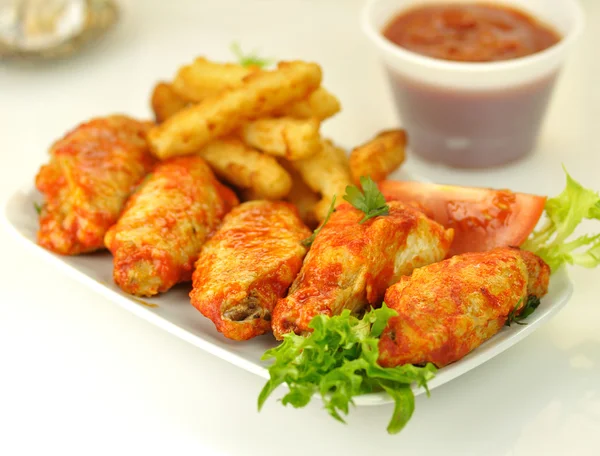 Hot chicken wings with fried potatoes — Stock Photo, Image