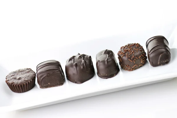 Sortimento de doces de chocolate em uma placa branca — Fotografia de Stock
