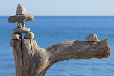 Stone man on dead tree against lake Ontario clipart