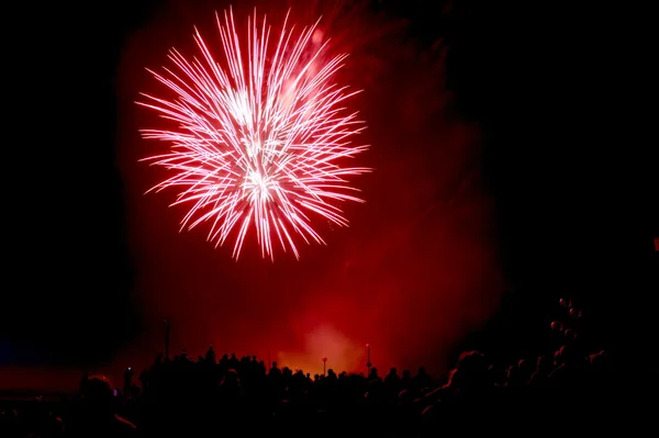 Één rode vuurwerk uitbarsting met menigte — Stockfoto
