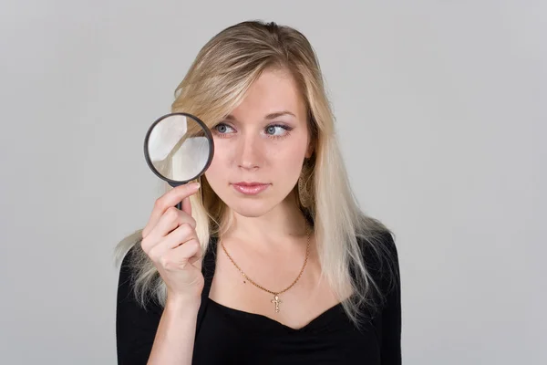 stock image The girl looking through a magnifying glass