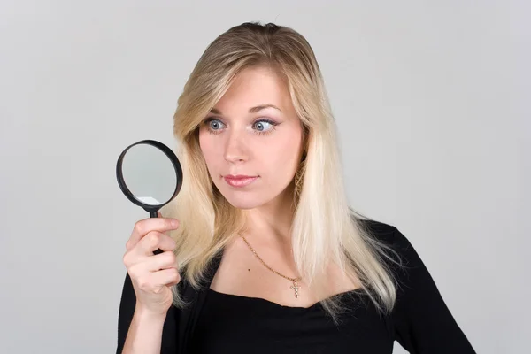 stock image The girl looking through a magnifying glass