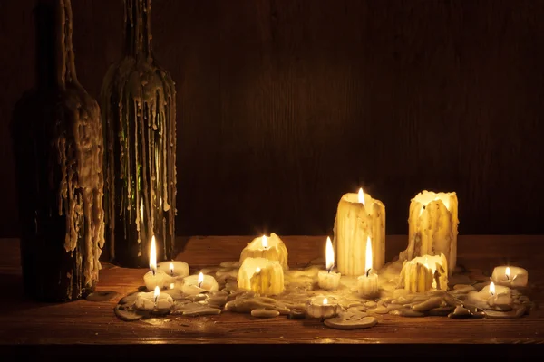Tání svíčka v dřevěné police s lahví — Stock fotografie