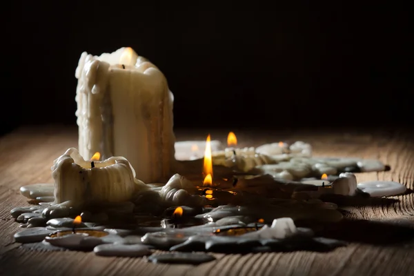 Тающие свечи с огнем на деревянной полке — стоковое фото