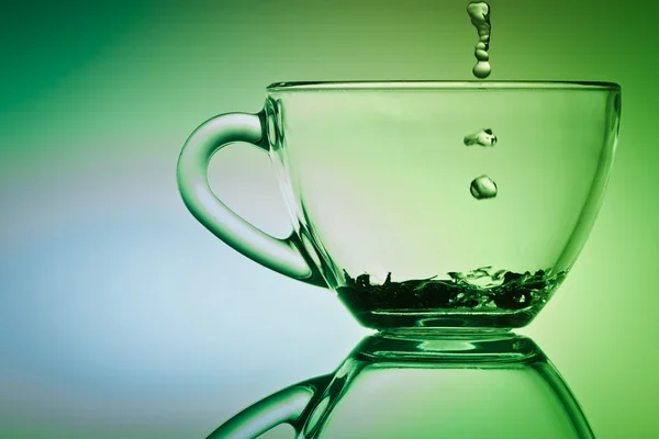 お茶のカップの下に流れ落ちる水のドロップします。 — ストック写真