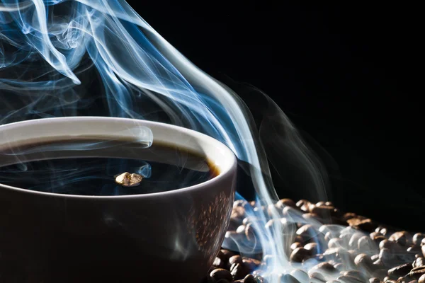Жареный кофе и чашка кофе на черном фоне — стоковое фото