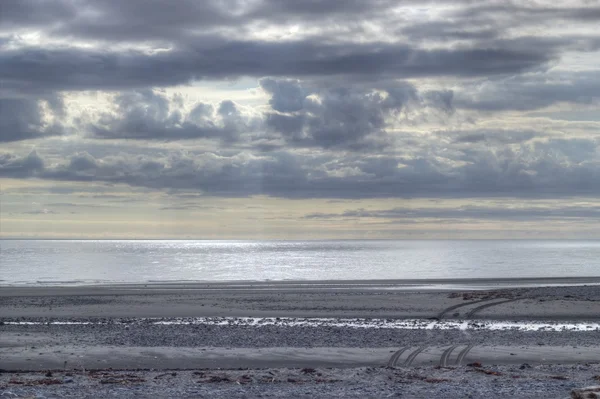Пляж в сумерках со следами шин на песке — стоковое фото