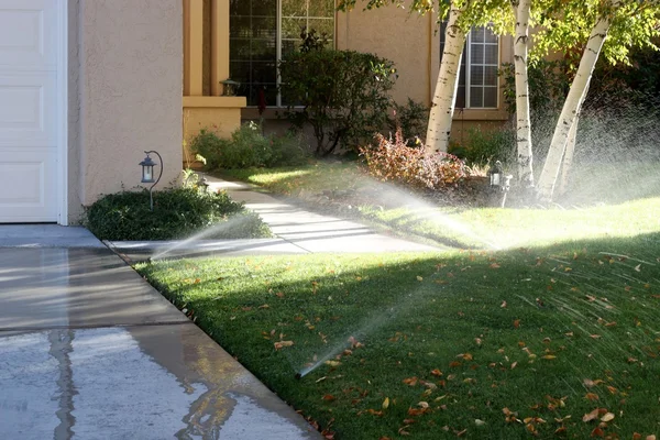 Sprinklers running onto the sidewalks of a typical American trac — Stock Photo, Image