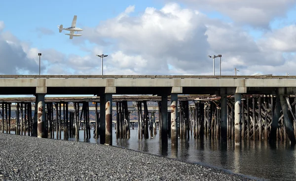 Низколетящий морской самолет над коммерческим причалом — стоковое фото